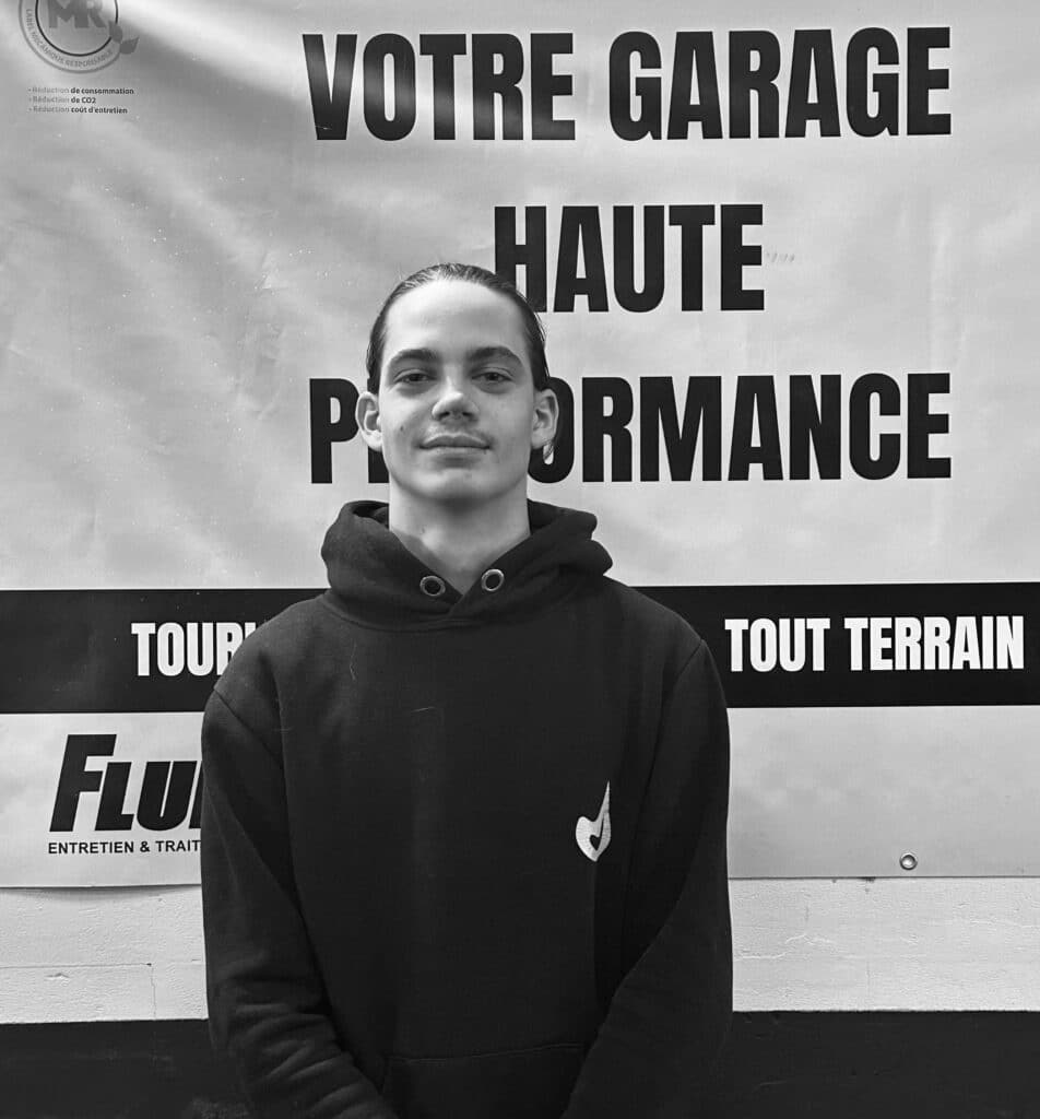 Garage Haute Performance : Entretien Automobile Jeune homme souriant devant une bannière "VOTRE GARAGE HAUTE PERFORMANCE" et "TOUT TERRAIN".